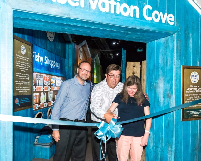 Courgeous fundraiser Suzannah Foulds cuts the ribbon as Max Leviston of Brighton Sea Life Centre with Andy Bool of the Sea Life Trust declare Conservation Cove open. photo ©Julia Claxton- graphics fifty50